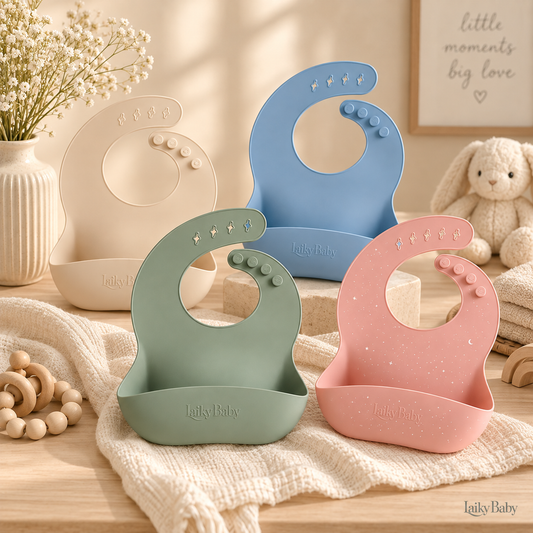 Four Laiky Baby silicone baby bibs with integrated suction bases in beige, blue, sage green, and dusty pink, arranged on a cream knit blanket with wooden toys and a plush bunny in a warm, styled nursery setting.